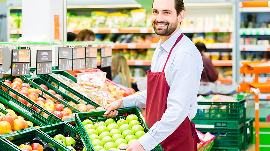 Mitarbeiter füllt Regal in Bio-Supermarkt auf